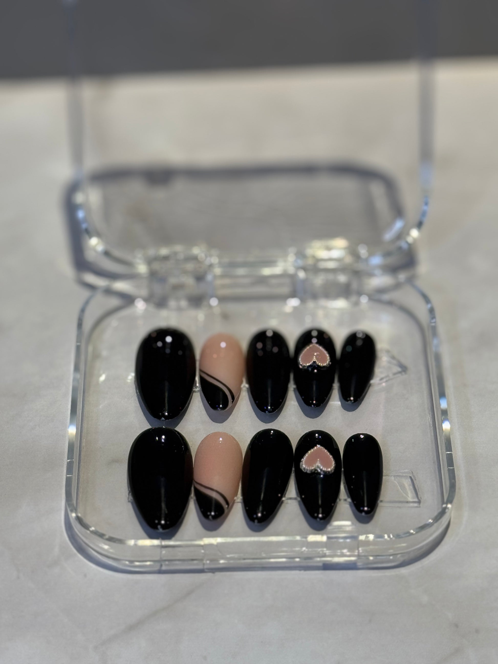 Dark black nails with elegant French tip detailing and a charming heart pendant accent. Perfect for creating a mysterious, sophisticated look with classic French manicure styling that delivers polished glamour. Ideal for expressing your unique personality and style with confidence.