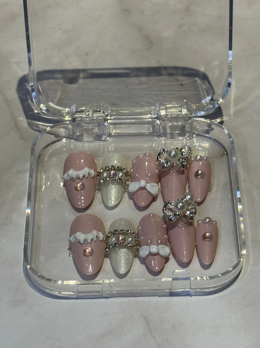 Almond medium press-on nails with a sweet and feminine design. Handcrafted with decorative rhinestones, pearls, and adorable hanging charms for that perfect finishing touch