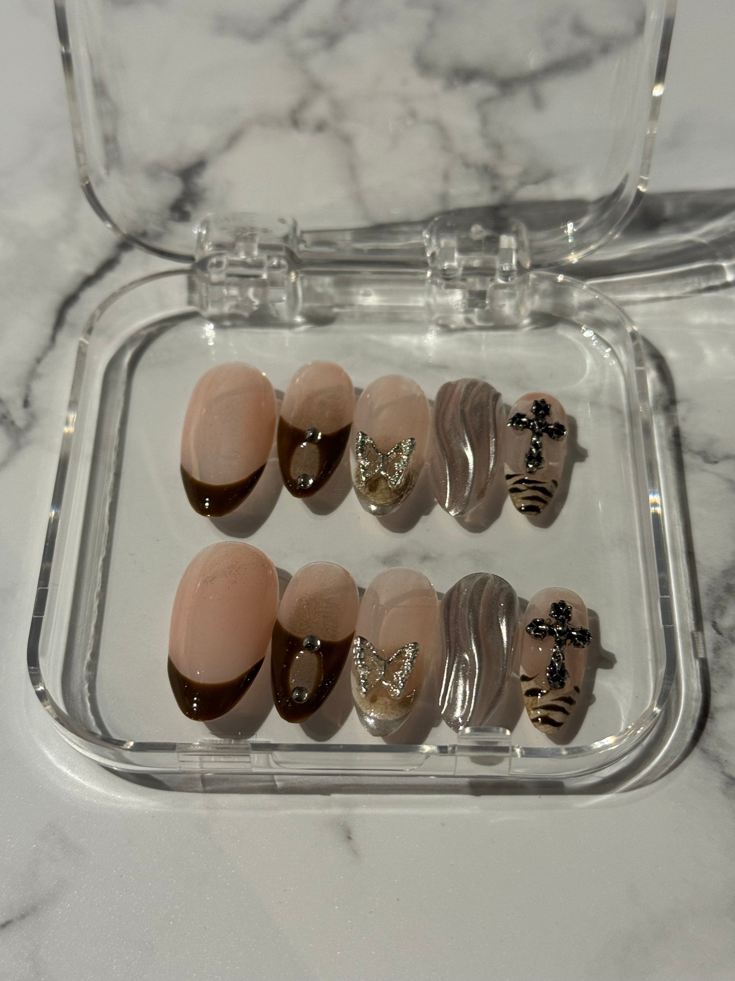 Brown nails featuring classic French tips accented with shimmering silver details. This mystical design combines gel finish with delicate charms for an ethereal, sophisticated look that balances elegance with an air of mystery. 
