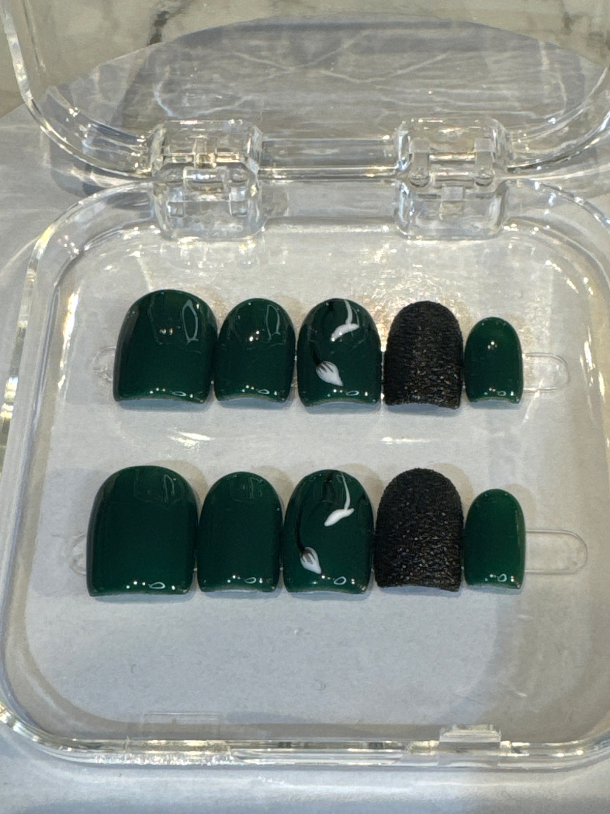 Luxury press-on nails, dark green, black 3D details, white flowers, glossy finish.