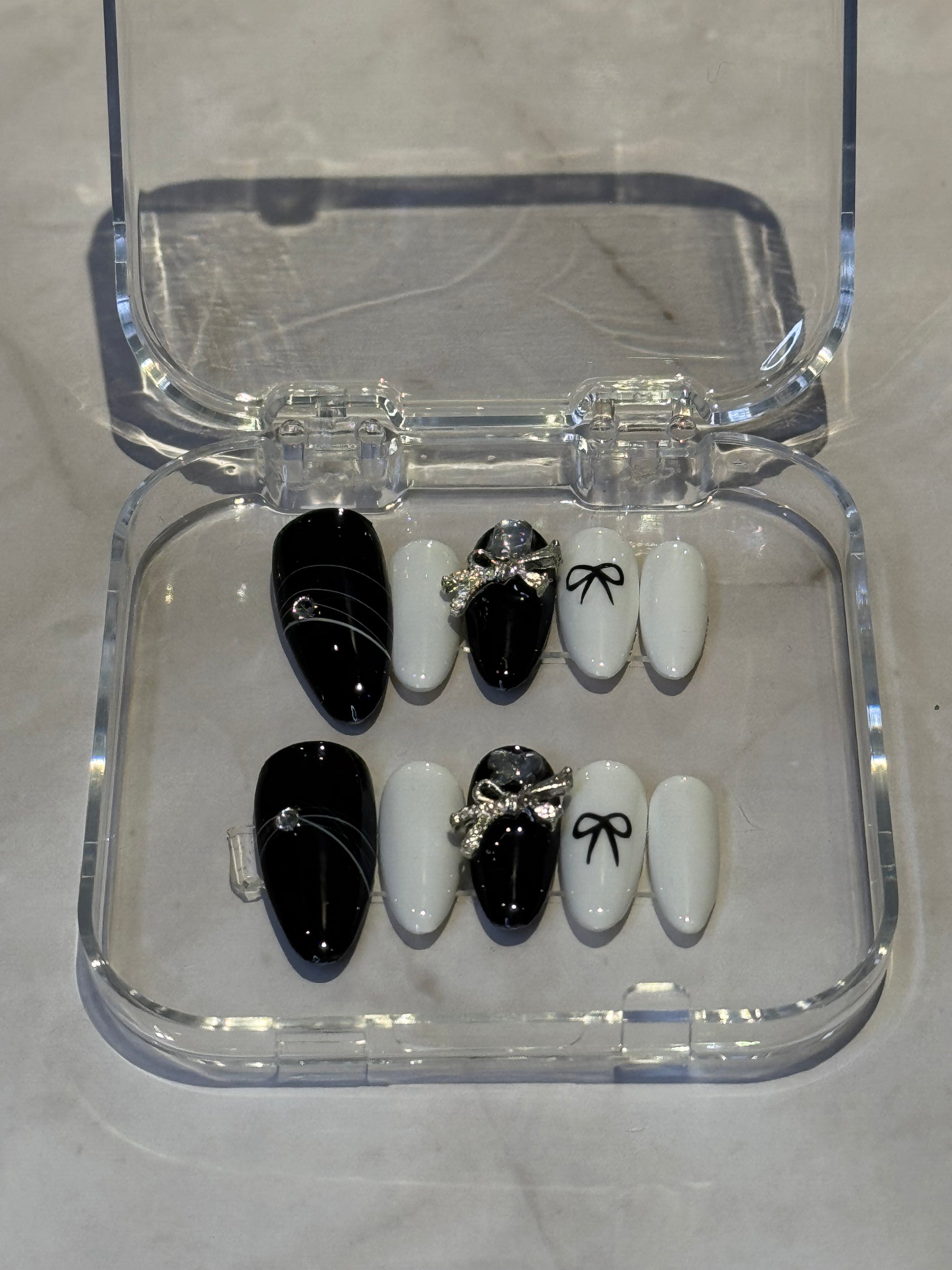 Medium almond nails with charming black and white embellishments.&nbsp;