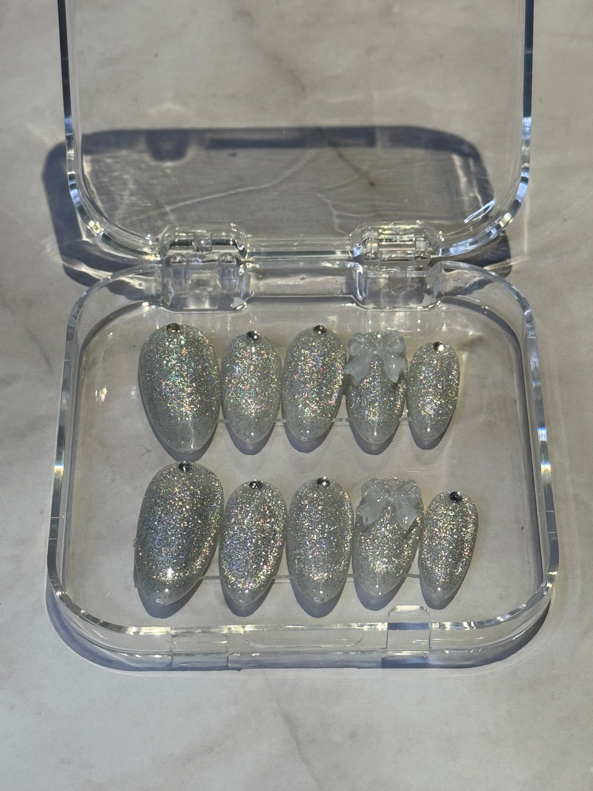 Cat eye, Medium Almond silver press on nails deliver instant glamour. Cute bow detail.