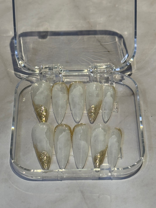 Stiletto long nails with beautiful hand-painted marbled design in white tones. Finished with luxurious gold effects for an elegant, goddess-like appearance. Perfect for making a bold statement with premium nail art.