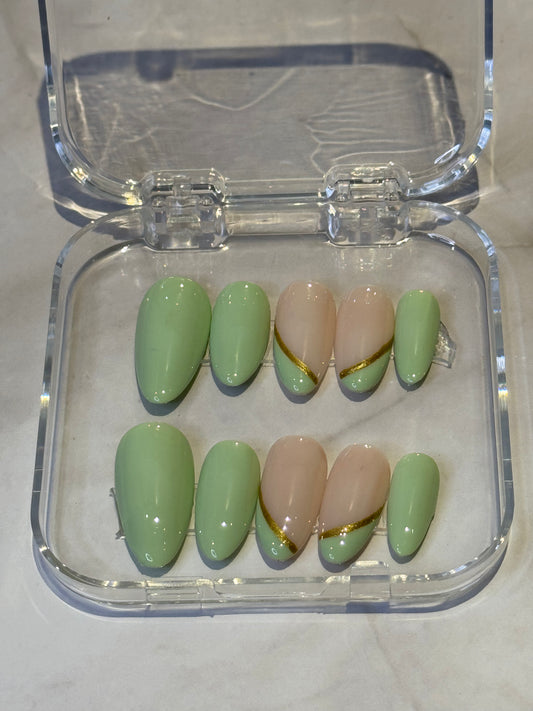 Medium almond nails with a sleek green French tip, enhanced with delicate hand-painted gold details.&nbsp;