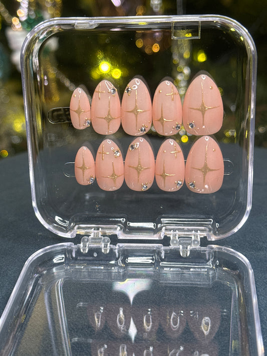 Luxury press-on nails, light peach-colored, gold stars, diamonds, Huntrix.
