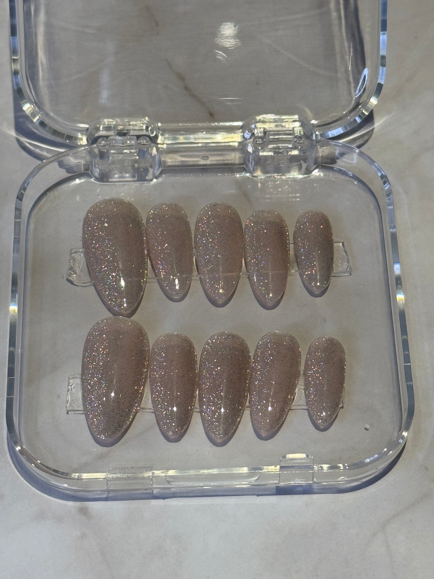Almond medium press-on nails in a soft natural nude shade with delicate silver glitter . The perfect balance of understated elegance and subtle sparkle for any occasion. Easy application, comfortable wear, and effortlessly chic style.